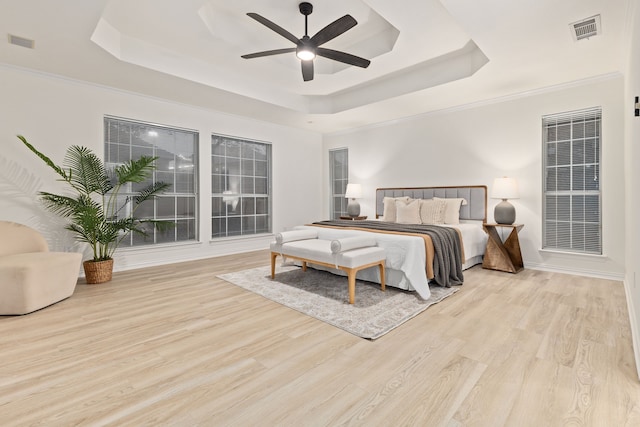 bedroom with a raised ceiling, light hardwood / wood-style floors, and ceiling fan