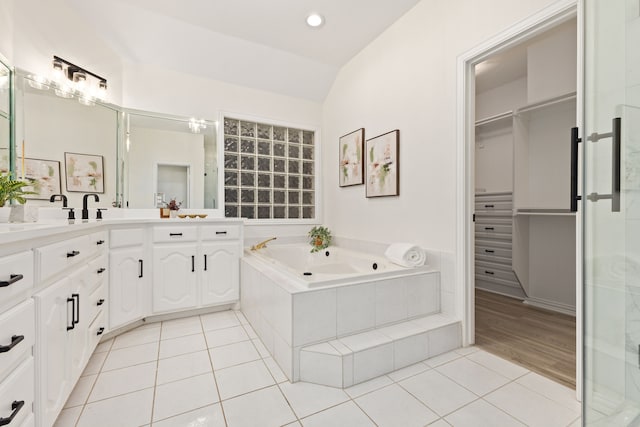 bathroom featuring vaulted ceiling, tile patterned flooring, vanity, and tiled tub