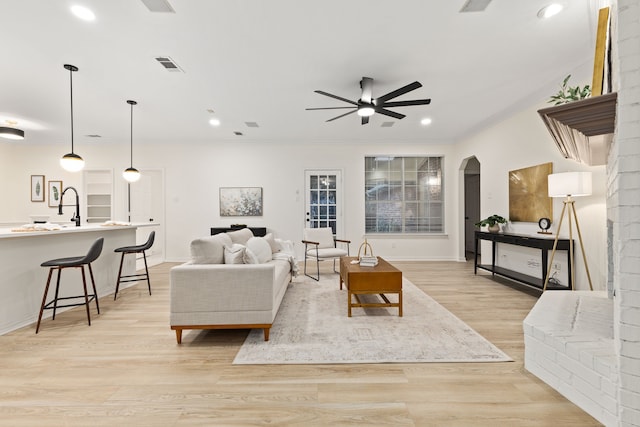 living room featuring light hardwood / wood-style floors, ceiling fan, and ornamental molding