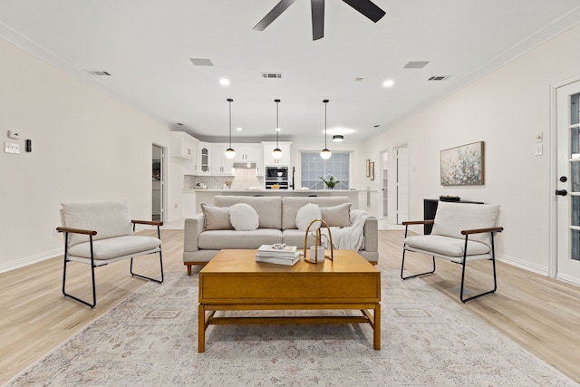 living room featuring ceiling fan, ornamental molding, and light hardwood / wood-style floors