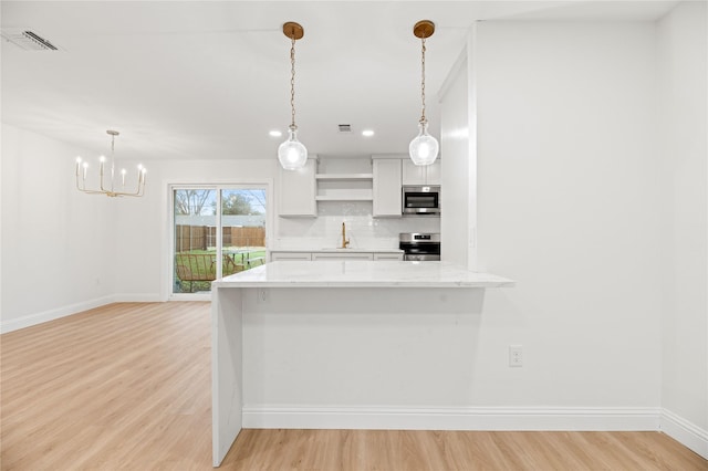 kitchen with light stone counters, appliances with stainless steel finishes, white cabinets, backsplash, and open shelves