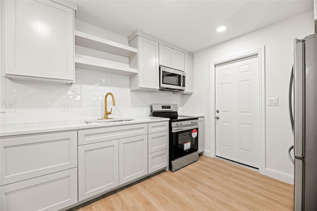 kitchen featuring stainless steel appliances, white cabinets, a sink, open shelves, and light wood-style floors