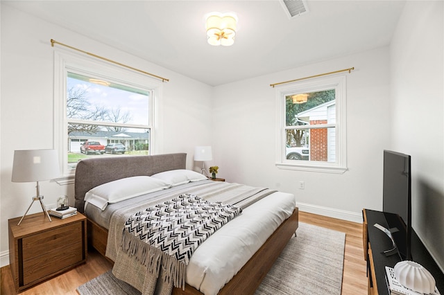 bedroom with visible vents, baseboards, and wood finished floors