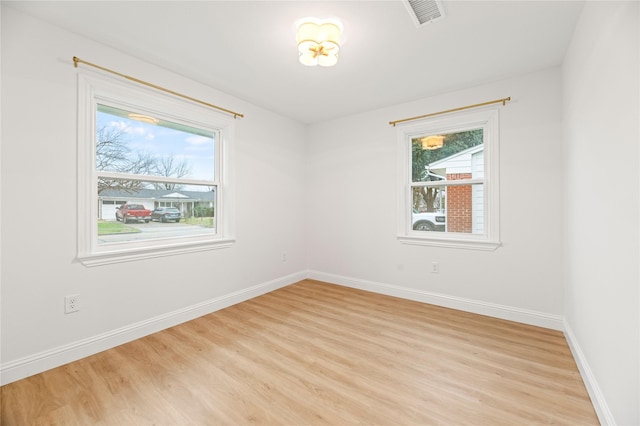 empty room featuring baseboards, visible vents, light wood-style flooring, and a healthy amount of sunlight