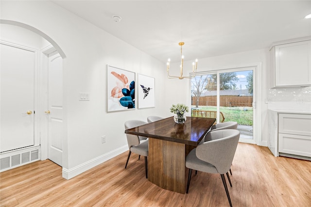 dining area with light wood-type flooring, visible vents, and arched walkways