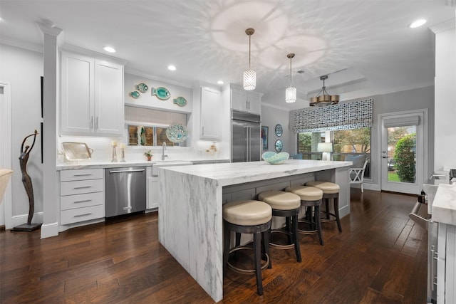 kitchen featuring white cabinetry, hanging light fixtures, a center island, appliances with stainless steel finishes, and crown molding