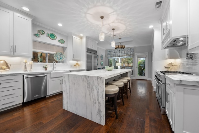 kitchen with sink, a center island, white cabinetry, pendant lighting, and premium appliances