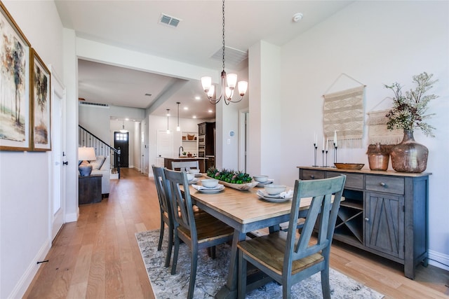 dining room with light hardwood / wood-style floors and an inviting chandelier