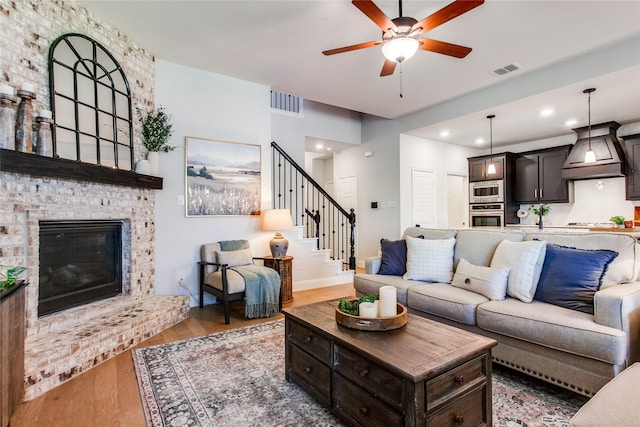 living room featuring ceiling fan, a brick fireplace, and hardwood / wood-style floors