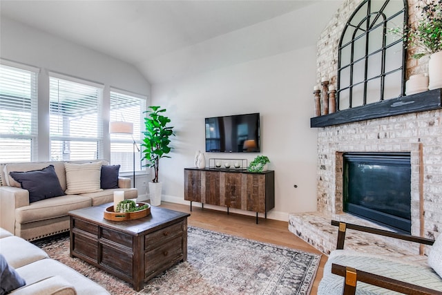 living room featuring a brick fireplace, hardwood / wood-style flooring, and vaulted ceiling