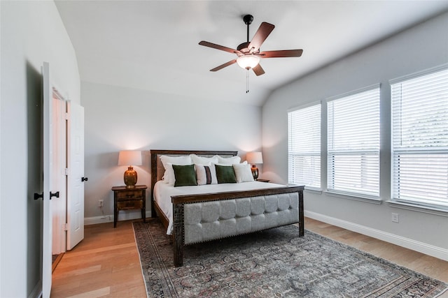 bedroom with ceiling fan, light hardwood / wood-style floors, and vaulted ceiling