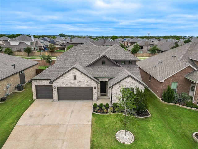 view of front of house with a garage, cooling unit, and a front lawn