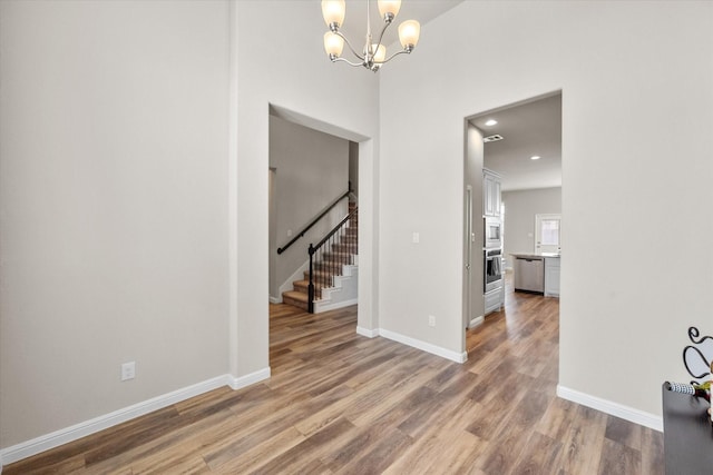 interior space featuring stairs, baseboards, an inviting chandelier, and light wood-style floors