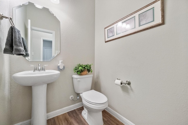 half bath featuring toilet, baseboards, and wood finished floors