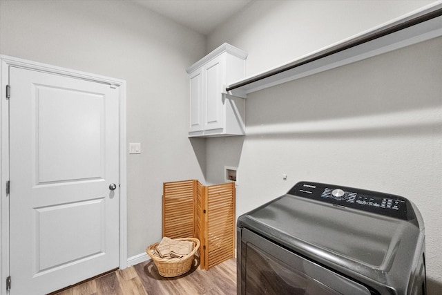 washroom featuring washer / clothes dryer, wood finished floors, cabinet space, and baseboards