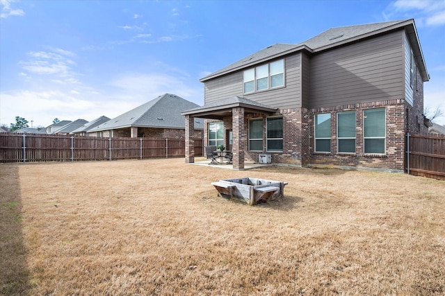 back of property featuring a yard, a patio, brick siding, and a fenced backyard