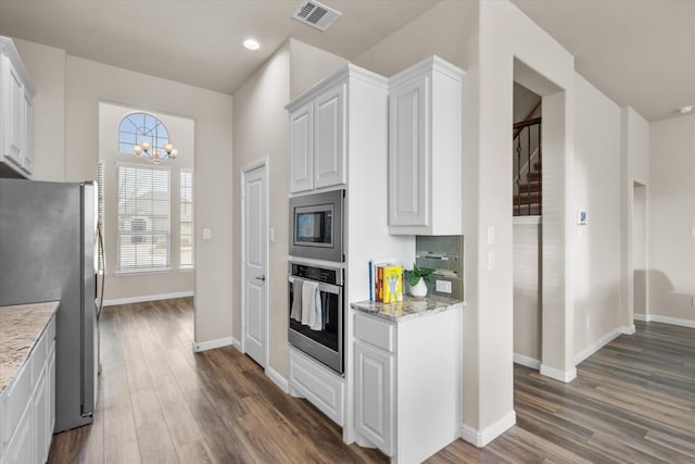 kitchen with stainless steel appliances, dark wood-style flooring, visible vents, and light stone counters