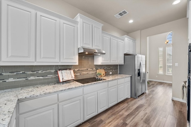 kitchen with visible vents, white cabinets, black electric stovetop, under cabinet range hood, and stainless steel refrigerator with ice dispenser