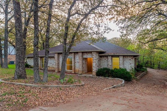 view of front of house with brick siding and a shingled roof