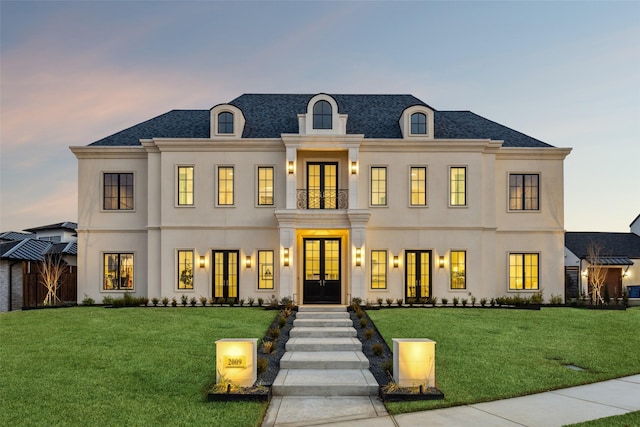 french country inspired facade featuring french doors and a yard