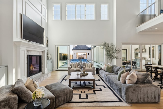 living room featuring a high end fireplace, a healthy amount of sunlight, and light hardwood / wood-style flooring