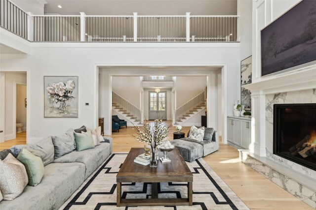 living room featuring light hardwood / wood-style floors, a premium fireplace, and a towering ceiling