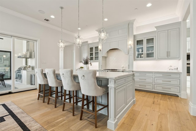 kitchen with light hardwood / wood-style flooring, decorative light fixtures, a kitchen island, backsplash, and a kitchen breakfast bar