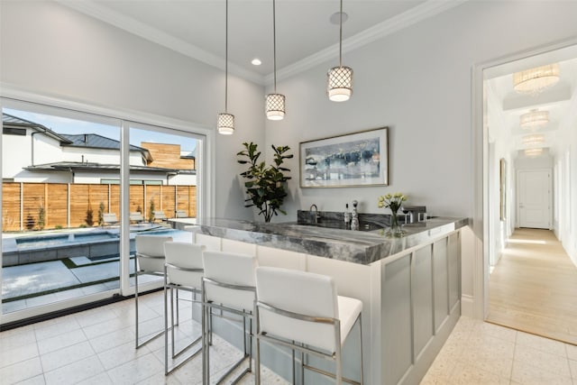 kitchen featuring white cabinetry, kitchen peninsula, hanging light fixtures, light tile patterned floors, and crown molding