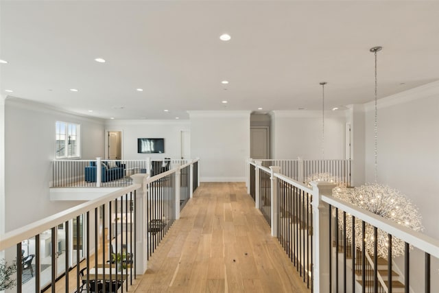 hall with light hardwood / wood-style floors, crown molding, and a notable chandelier