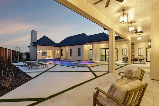 pool at dusk featuring pool water feature, a patio, an in ground hot tub, and ceiling fan