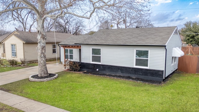 view of front of house featuring roof with shingles, brick siding, concrete driveway, and a front yard