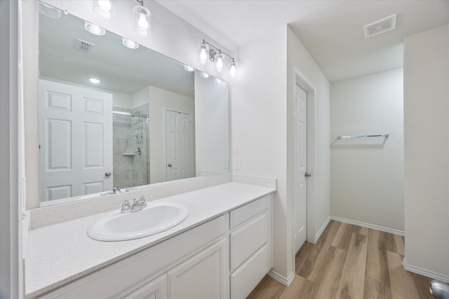 bathroom featuring hardwood / wood-style flooring, vanity, and walk in shower