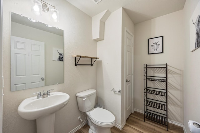 bathroom featuring wood-type flooring, toilet, and sink