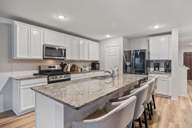 kitchen with sink, a center island with sink, appliances with stainless steel finishes, and white cabinetry