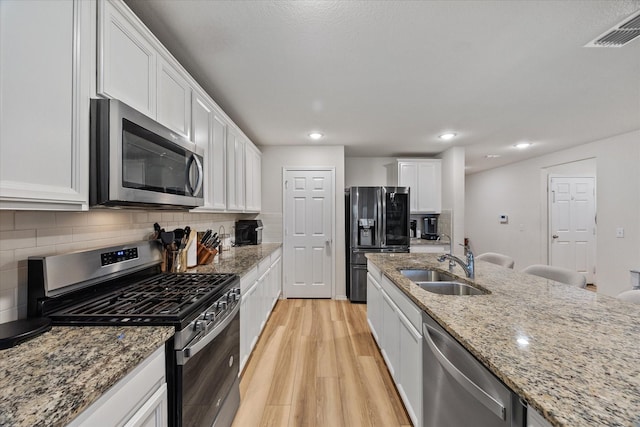 kitchen featuring appliances with stainless steel finishes, sink, light stone counters, and white cabinets