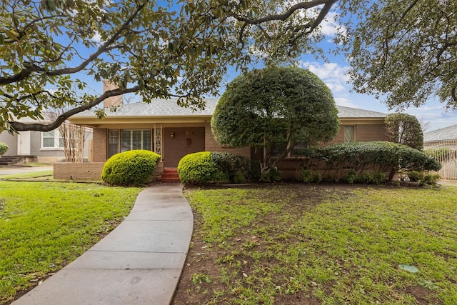 ranch-style home featuring brick siding, a front yard, and fence