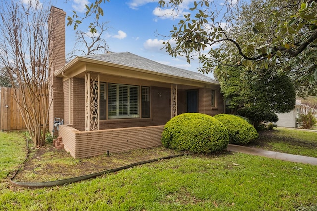 view of front of house with a chimney, fence, a front lawn, and brick siding