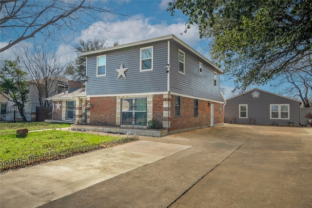 view of front of property with driveway, fence, a front lawn, and brick siding