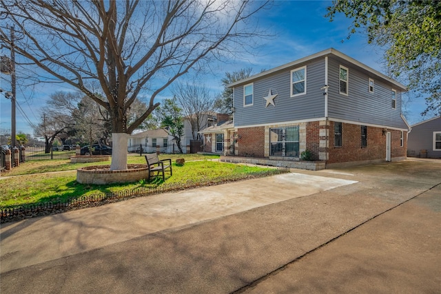 view of property exterior with concrete driveway, brick siding, a lawn, and fence