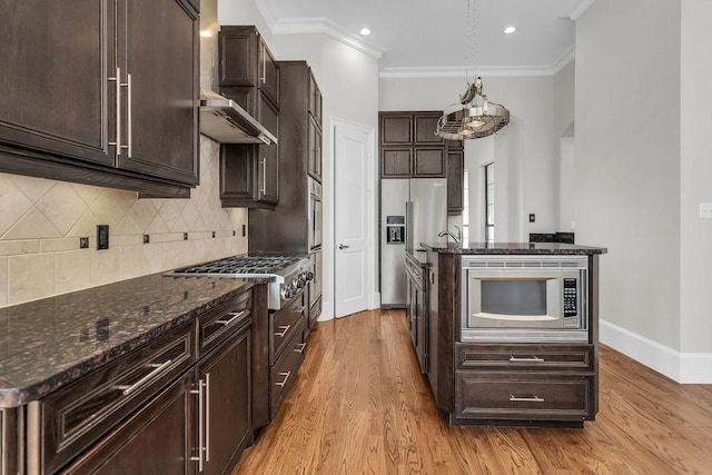 kitchen featuring appliances with stainless steel finishes, dark stone counters, pendant lighting, and light wood-type flooring