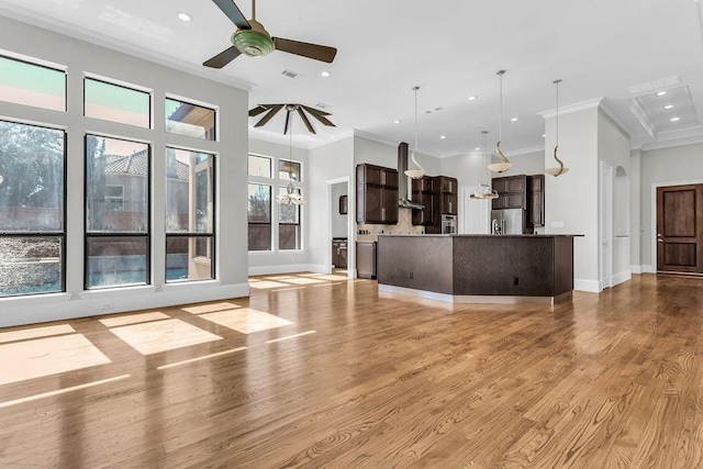 unfurnished living room with ceiling fan, crown molding, light wood-type flooring, and baseboards