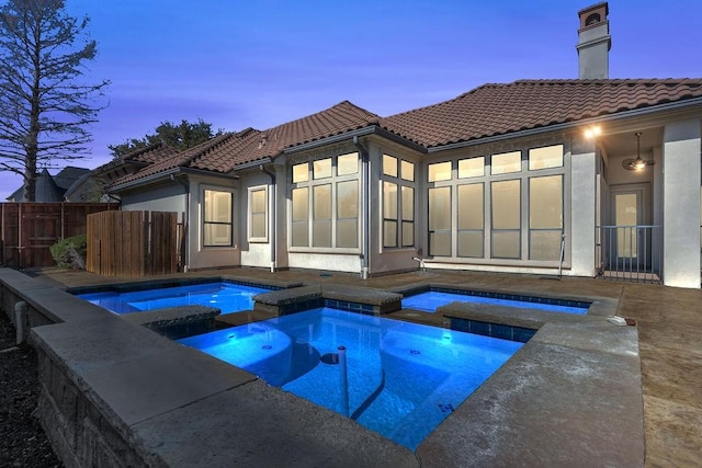 view of swimming pool featuring a pool with connected hot tub and fence