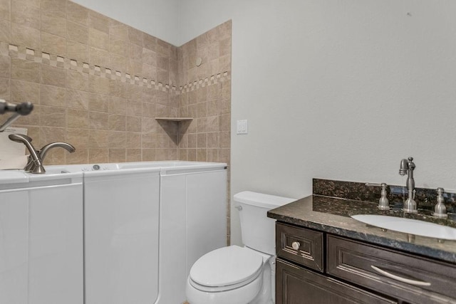 bathroom featuring toilet, vanity, and a bath