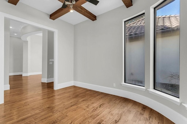 unfurnished room with a ceiling fan, wood finished floors, beam ceiling, and baseboards