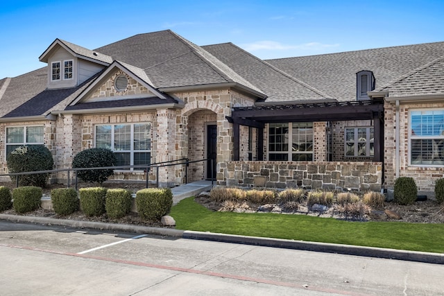 french country inspired facade featuring stone siding, fence, and a shingled roof