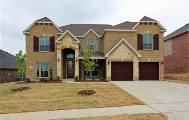 view of front facade with a garage, driveway, brick siding, and a front lawn