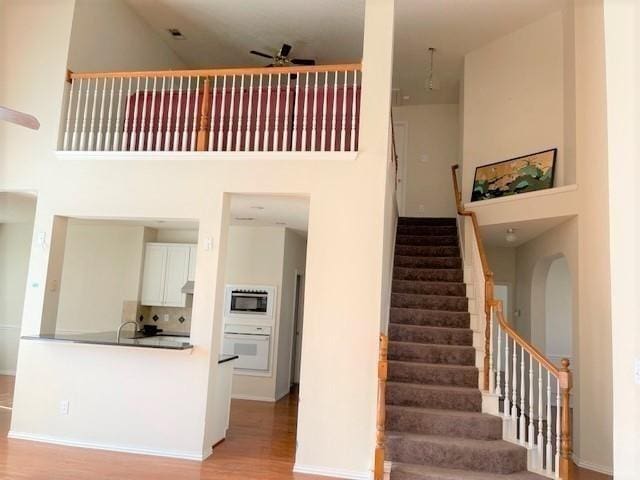 staircase with a high ceiling, hardwood / wood-style flooring, sink, and ceiling fan