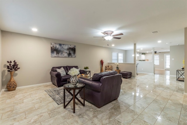 living area featuring a ceiling fan, a wealth of natural light, visible vents, and baseboards