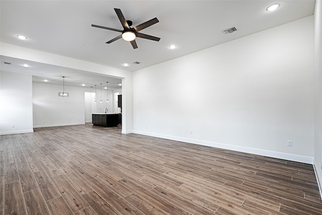 unfurnished living room featuring ceiling fan and dark hardwood / wood-style flooring