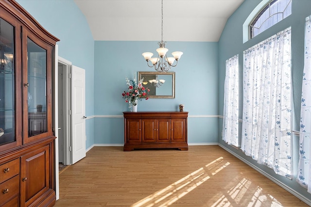 dining space featuring a notable chandelier, light hardwood / wood-style floors, and vaulted ceiling